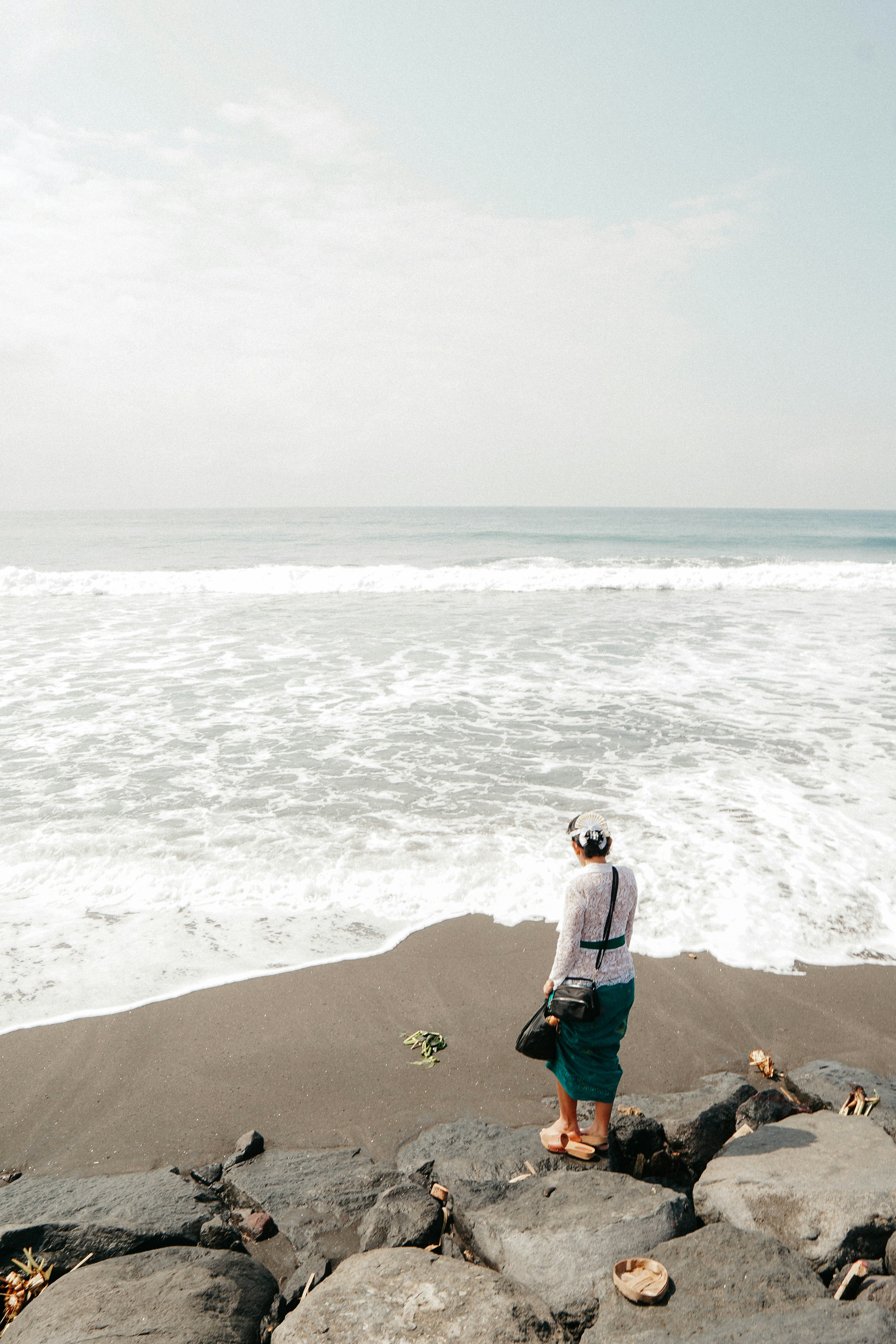 Woman in blue jacket and blue denim jeans sitting on brown sand near ...