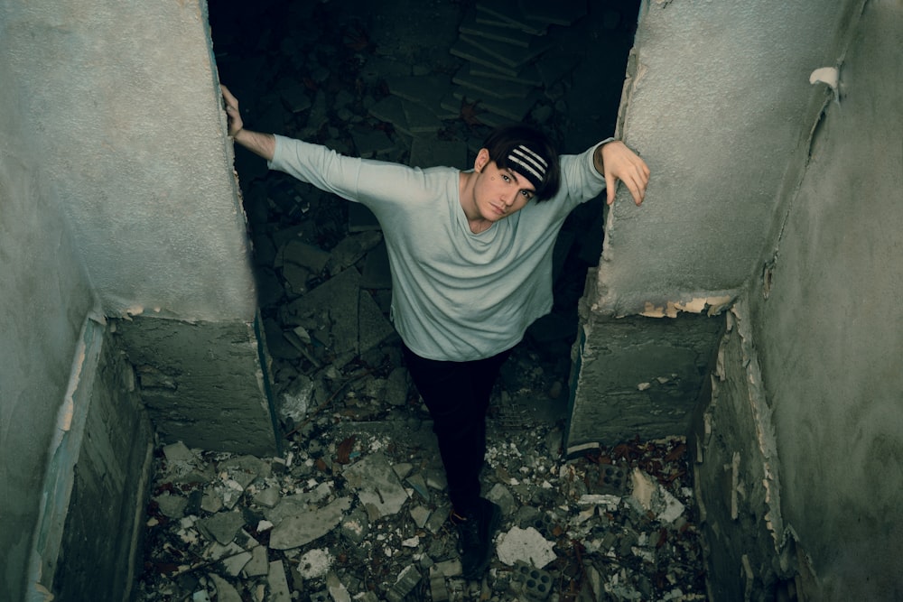 man in gray long sleeve shirt and black pants standing on gray concrete wall