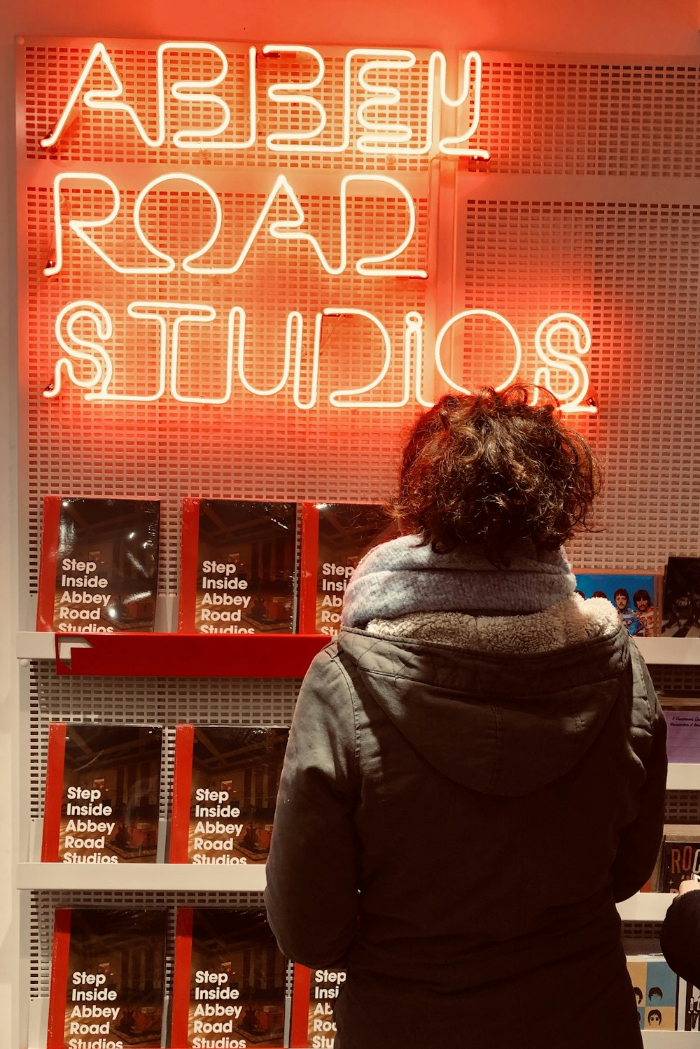 woman in gray scarf standing in front of red and white love neon signage