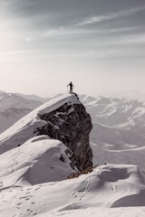 A lone traveler gazing at snow-capped Himalayan peaks during sunset.
