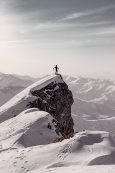 A lone traveler gazing at snow-capped Himalayan peaks during sunset.