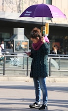 woman in black and red long sleeve shirt and blue denim jeans standing on sidewalk during