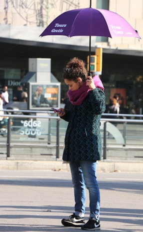 woman in black and red long sleeve shirt and blue denim jeans standing on sidewalk during