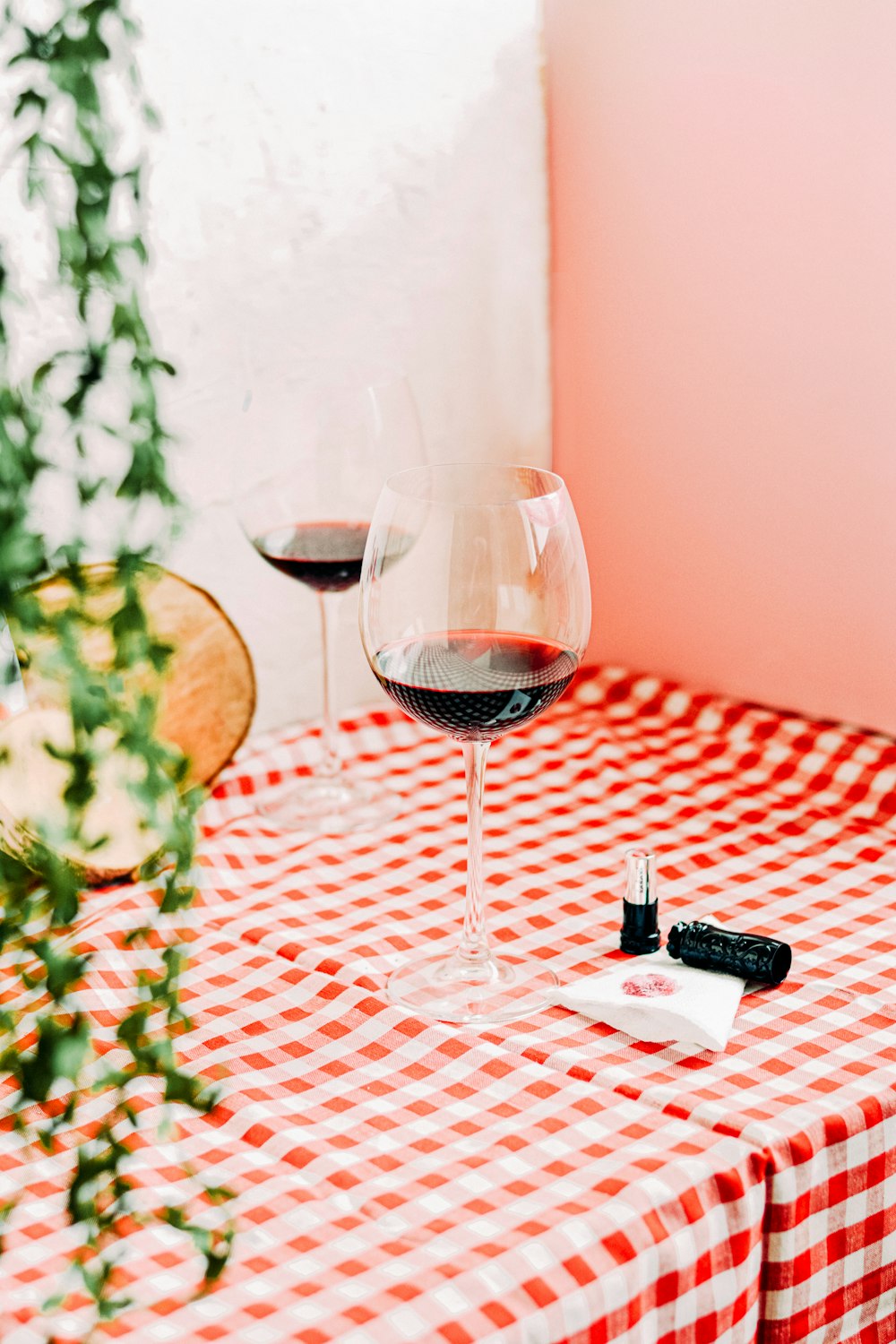 clear wine glass with red wine on red and white checkered table cloth