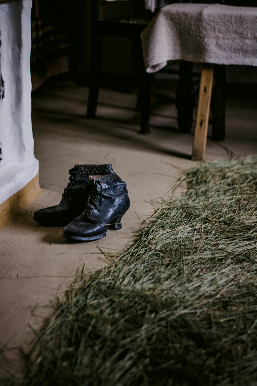 personne portant des bottes en cuir noir debout sur de l’herbe séchée brune