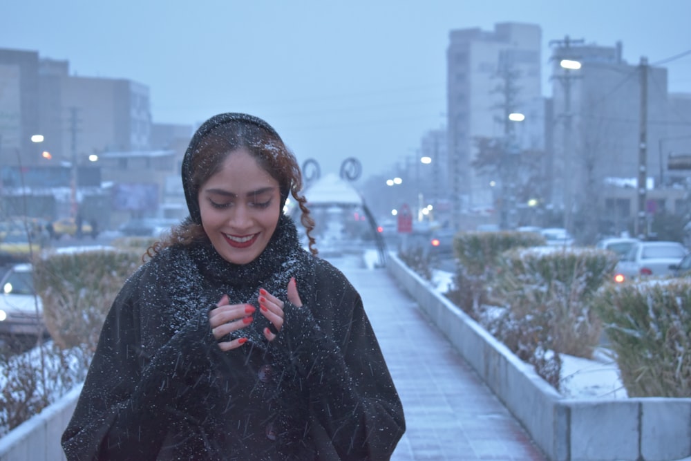 a woman standing on a sidewalk in the snow