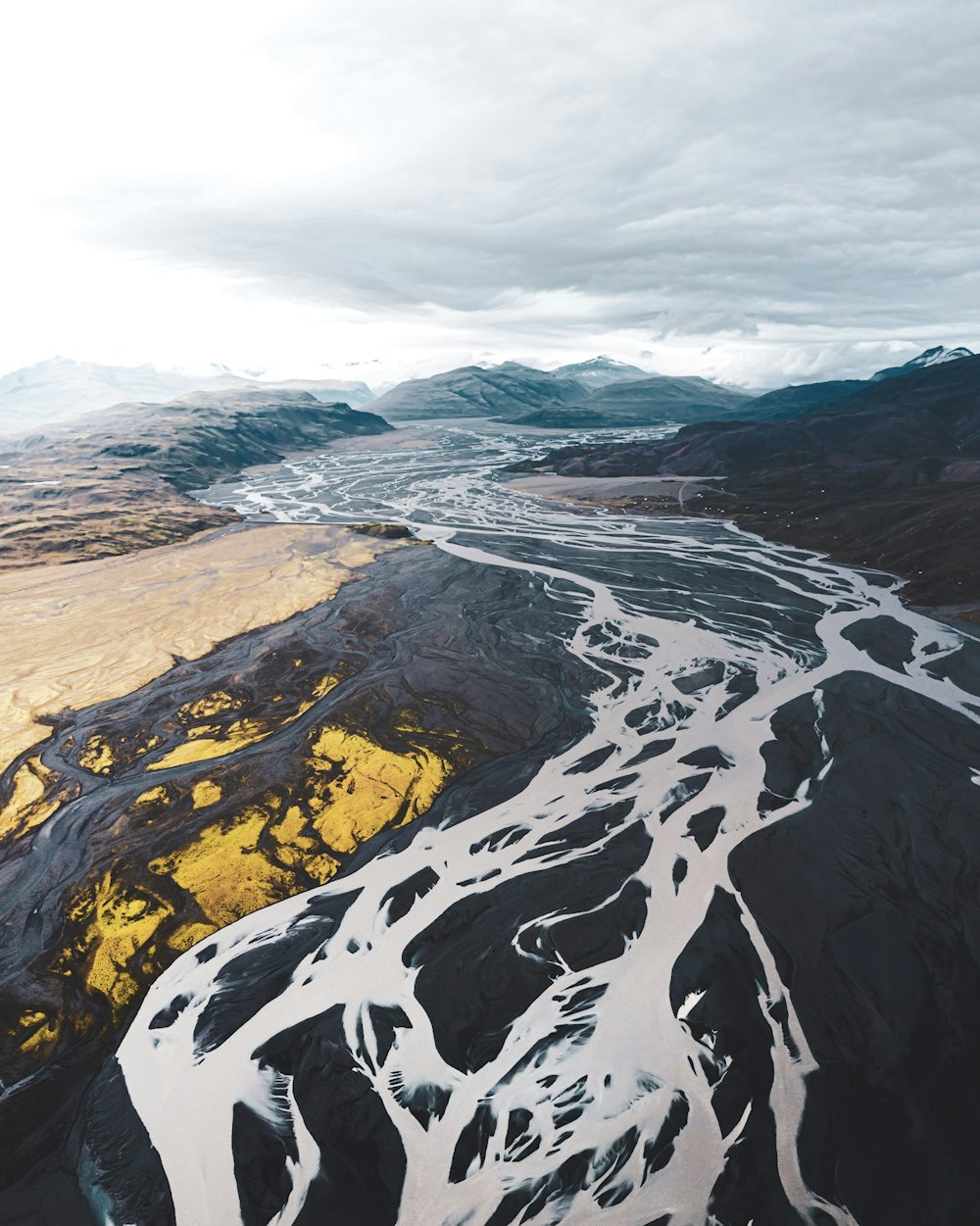 aerial view of black and white mountains under cloudy sky during daytime