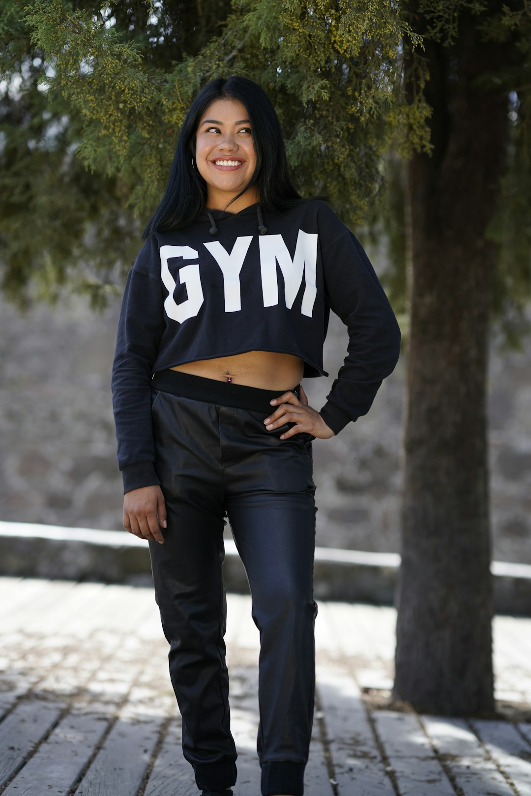 woman in black and white hoodie and blue denim jeans standing on gray concrete pathway during