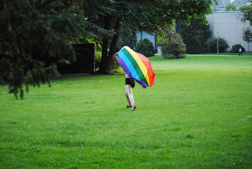 person holding multi colored umbrella walking on green grass field during daytime