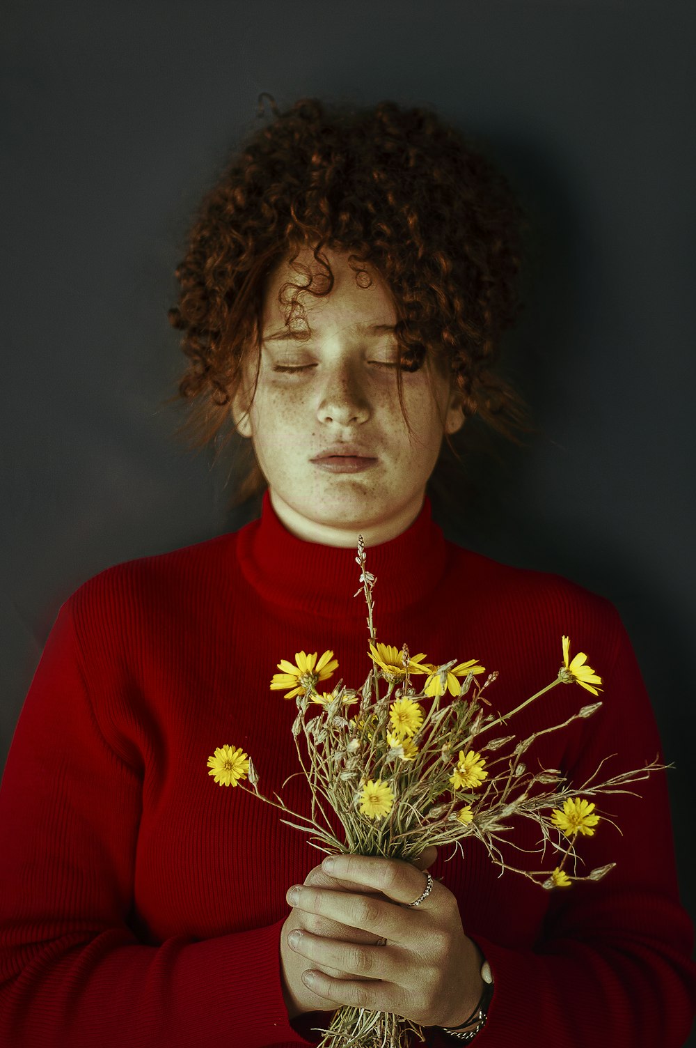 woman in red crew neck shirt holding yellow flowers