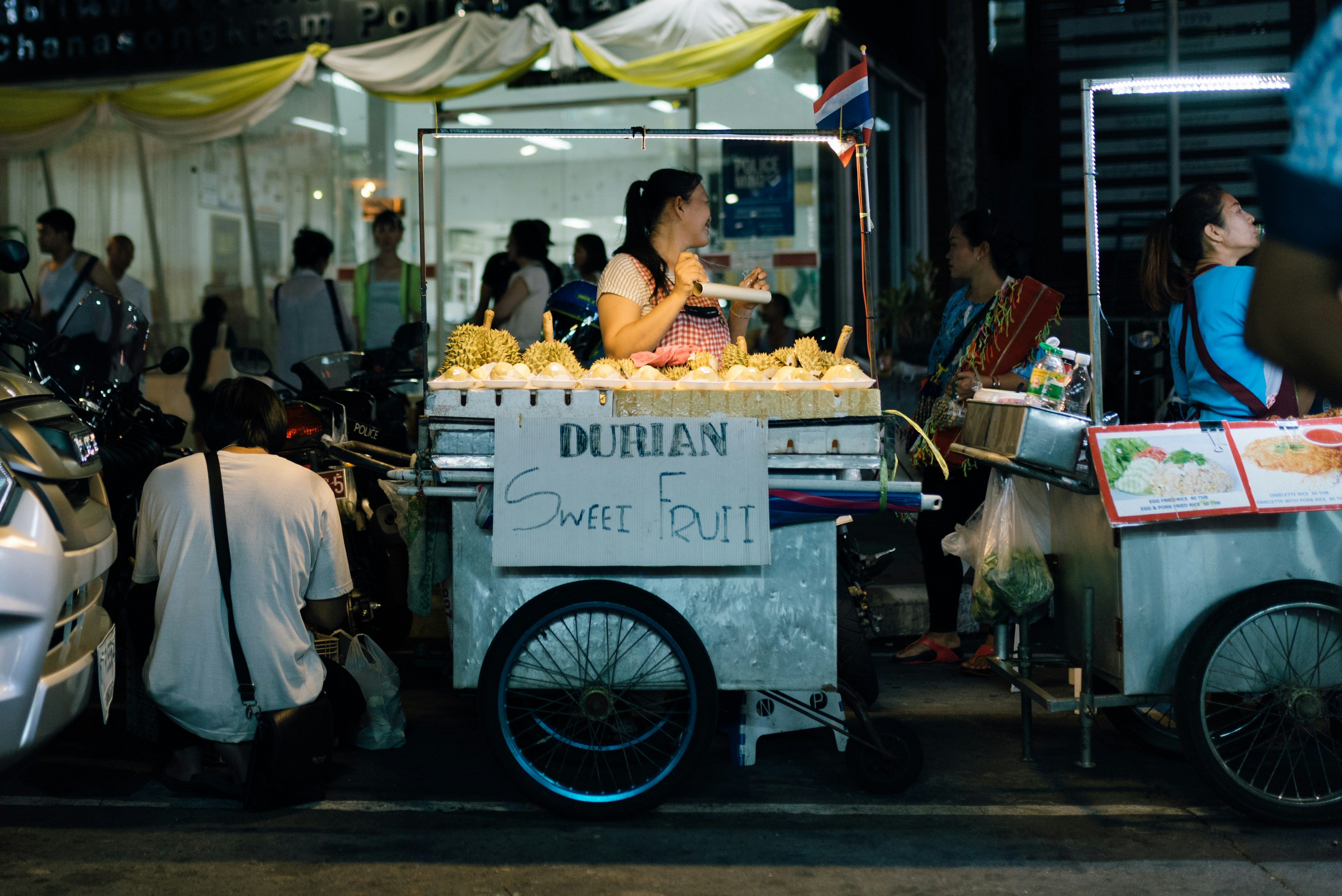 man in white long sleeve shirt standing in front of food cart