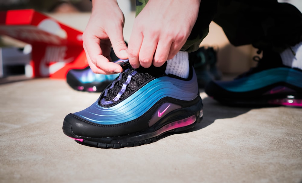 person holding black and pink nike athletic shoe