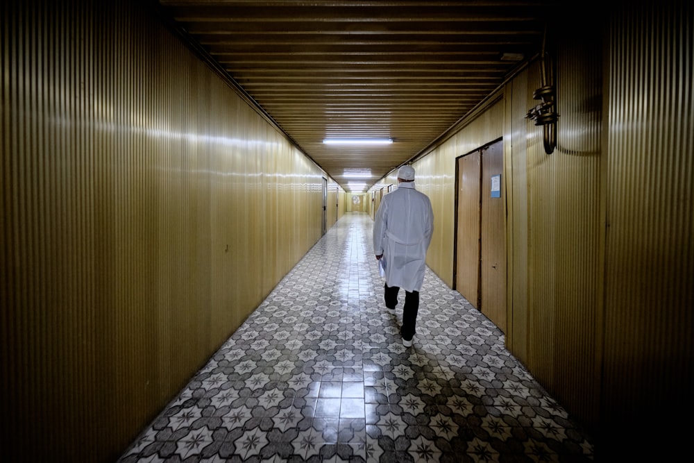 man in white dress shirt and black pants walking on hallway