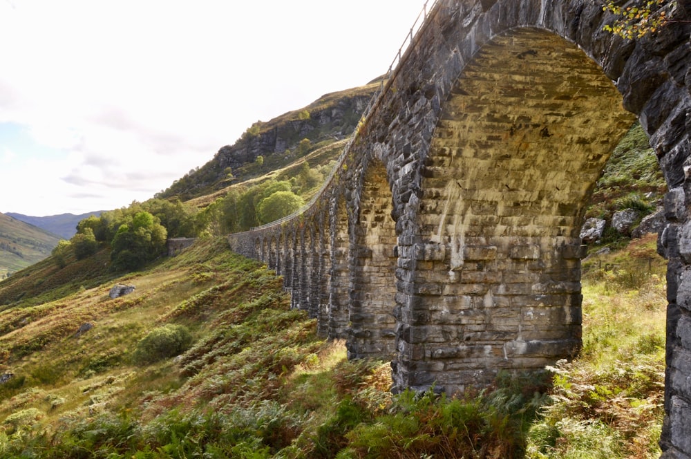 gray concrete bridge over green grass field during daytime