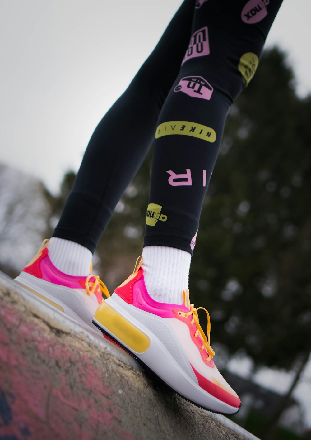 person in black pants wearing white pink and yellow nike sneakers