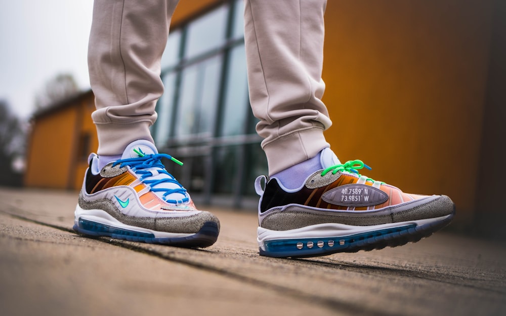 person in gray pants wearing blue and white nike sneakers