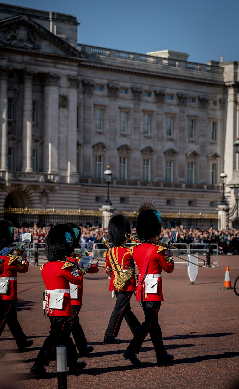 people in red uniform playing musical instruments in front of white concrete building during daytime