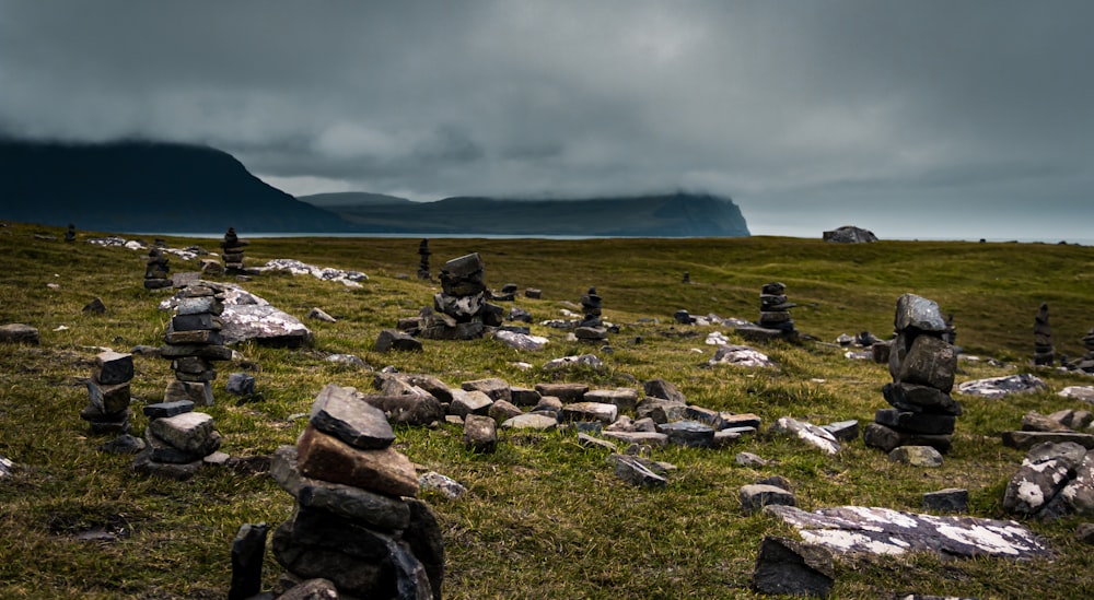 green grass field near mountain under white clouds during daytime