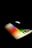 A laptop partially open with a glowing apple logo on the back. The keyboard and touchpad display a spectrum of vibrant colors, creating a visually striking effect against the dark background.