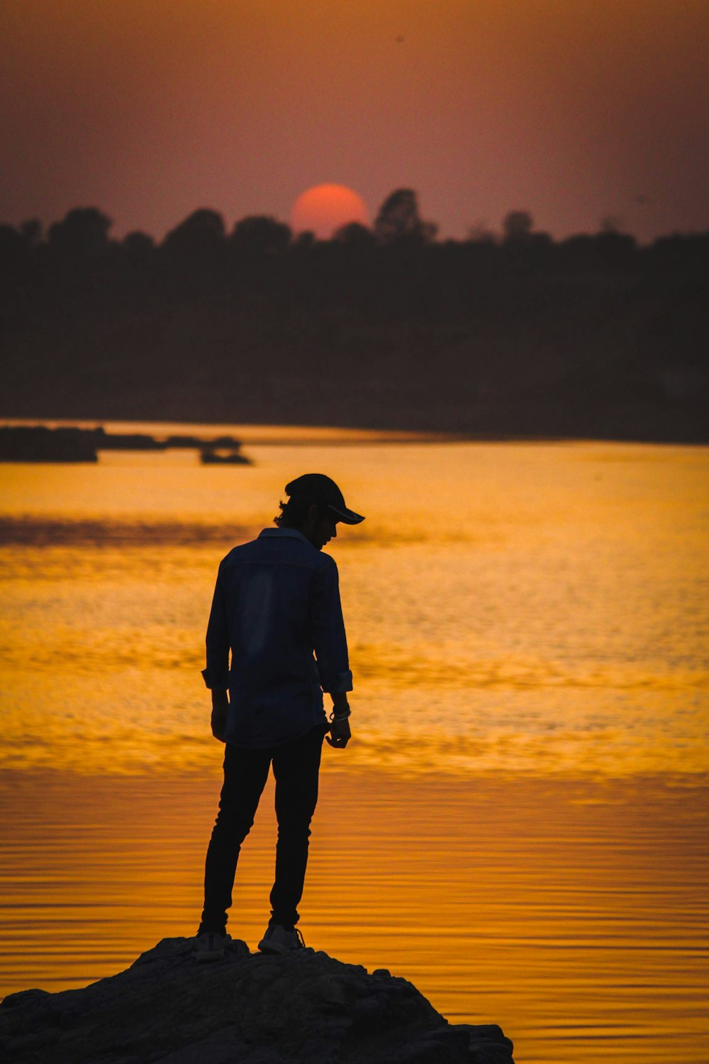 silhouette of man standing on seashore during sunset