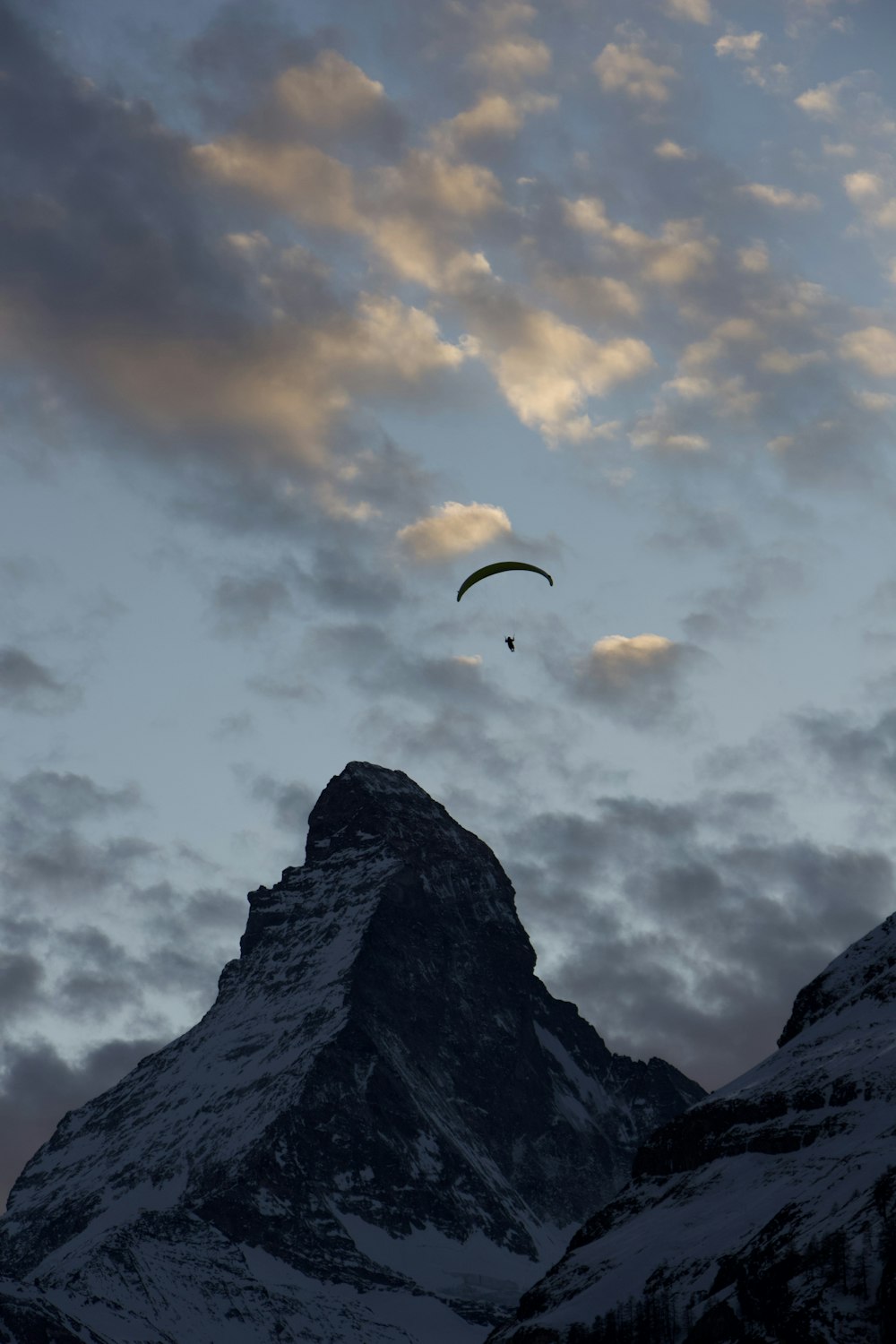 person in parachute over rocky mountain during daytime
