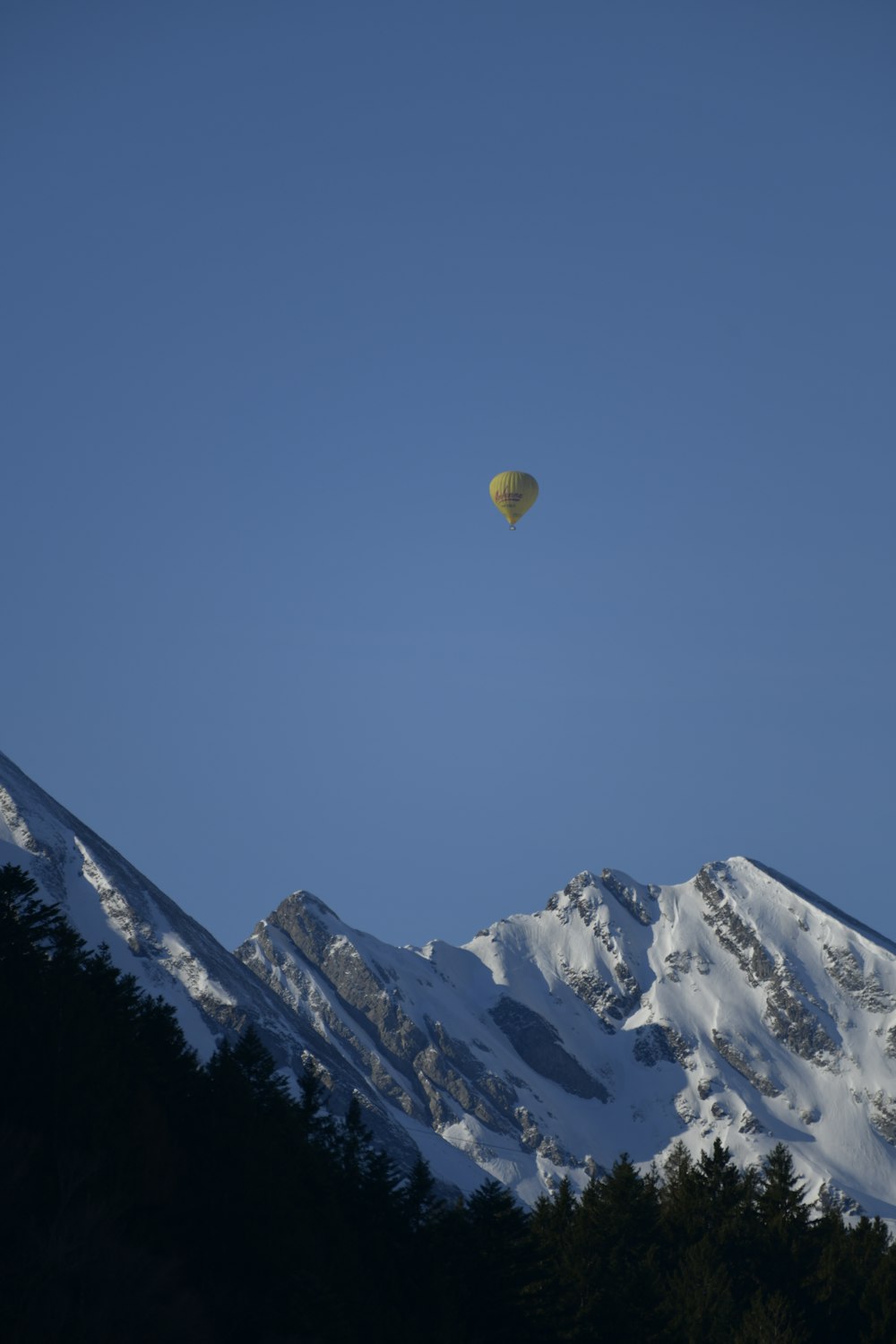 hot air balloon flying over snow covered mountain