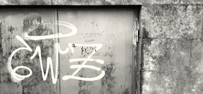 Collection of stencil artworks displayed on a weathered metal door in an alley.