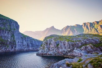 green and brown mountain beside body of water during daytime
