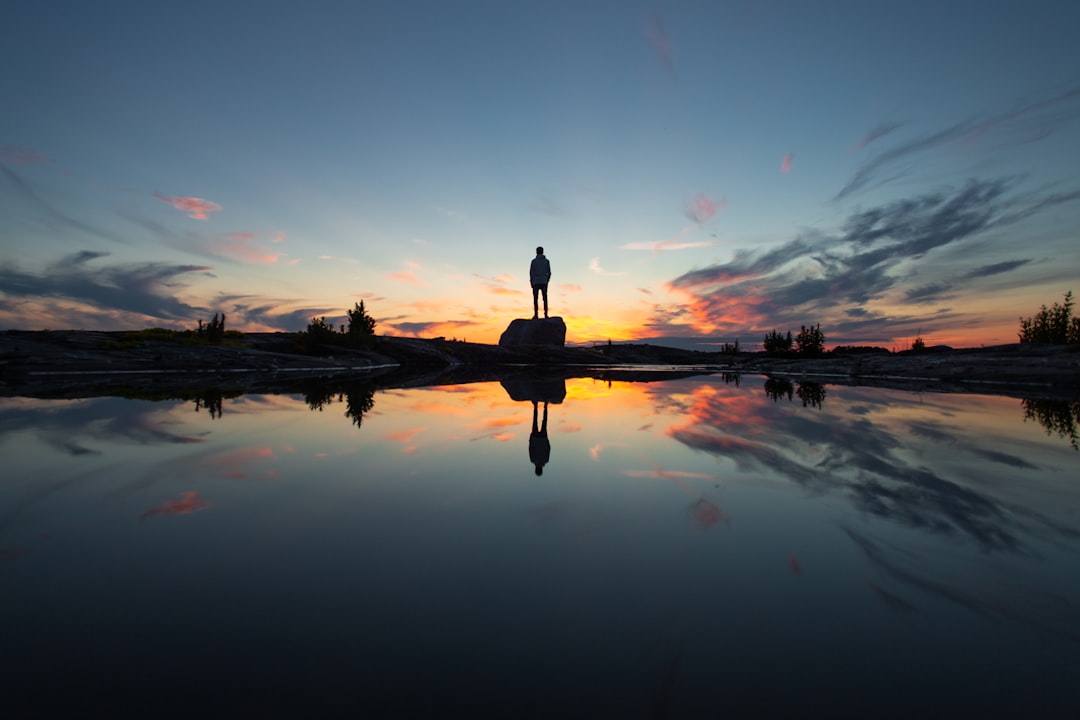 silhouette of man standing on dock during sunset
