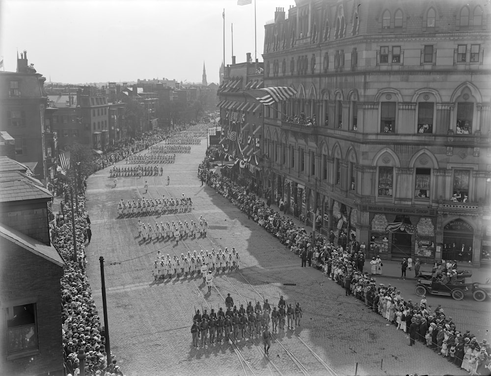 grayscale photo of people walking on street near building