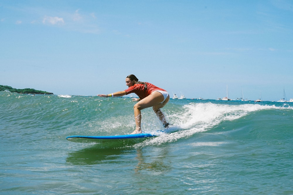 Frau im blau-weißen Neoprenanzug beim Surfen auf See tagsüber