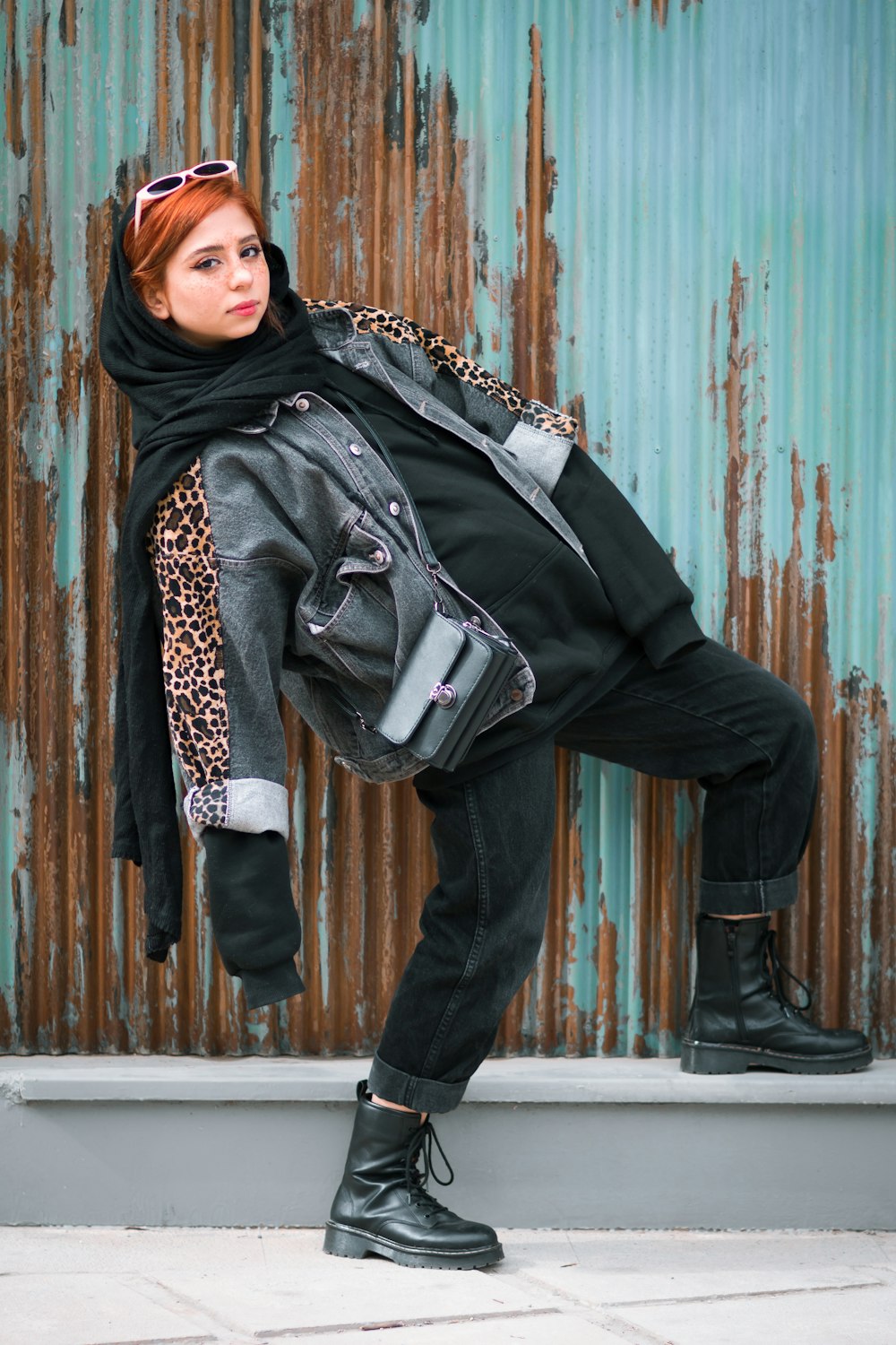 woman in black leather jacket and black pants standing beside brown wooden wall