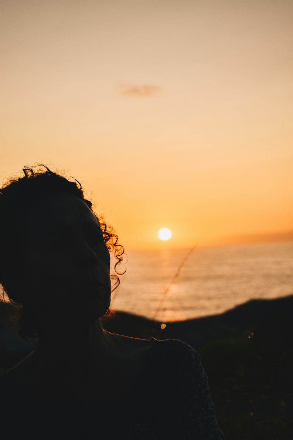 silhouette of woman near body of water during sunset