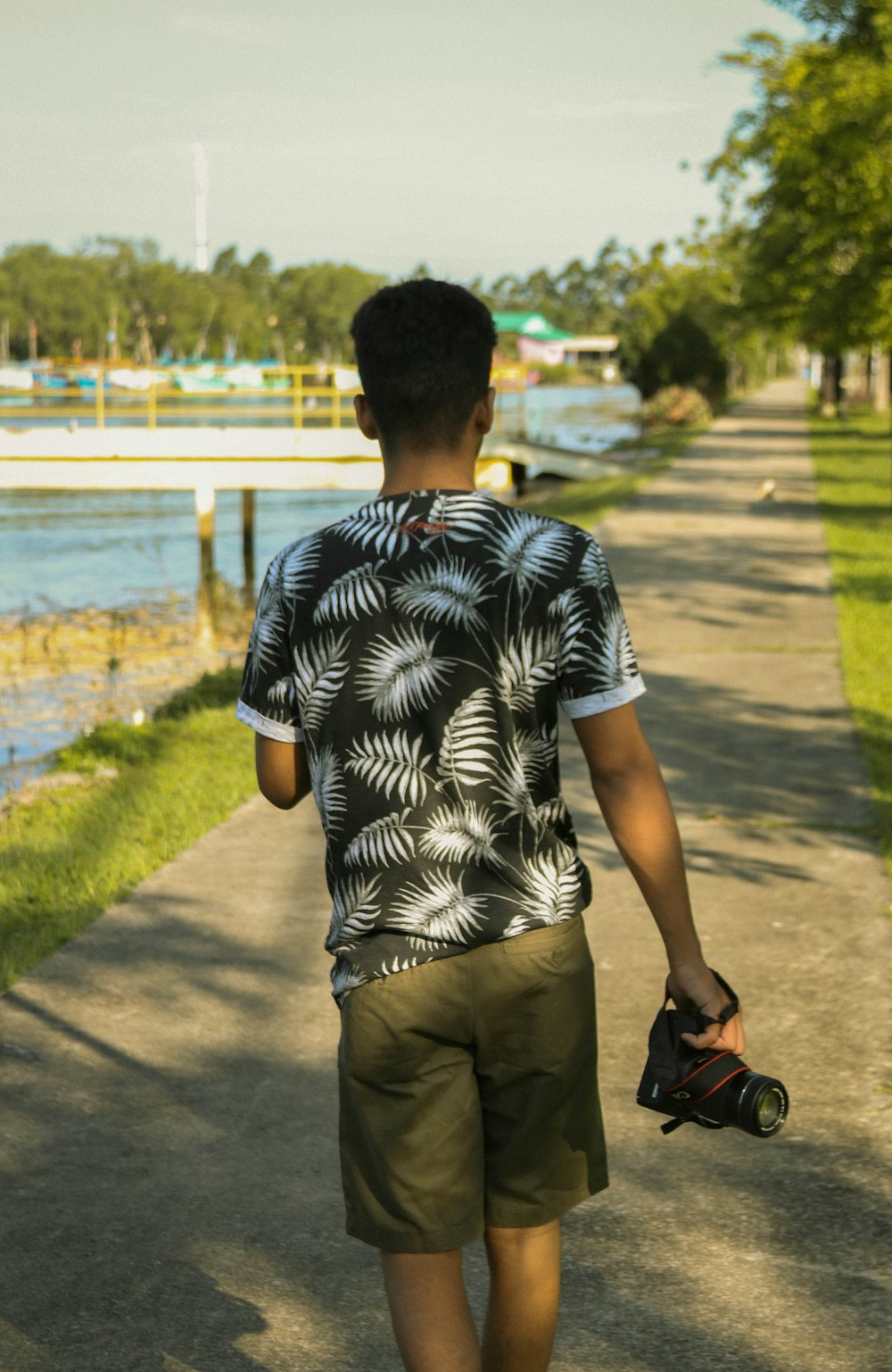 man in black and white stripe polo shirt and brown pants standing on sidewalk during daytime