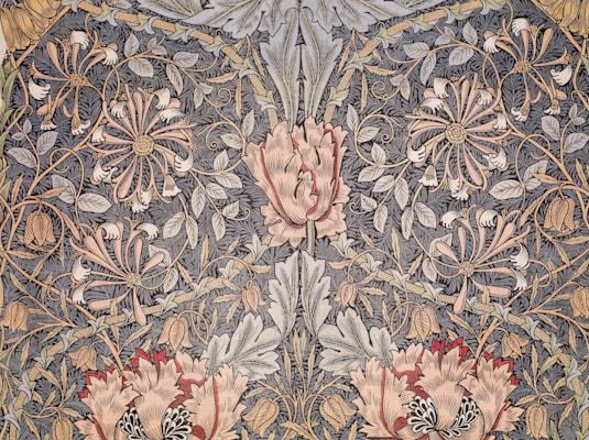 An intricate floral pattern featuring large pink and red flowers, surrounded by elaborate foliage and smaller delicate blooms with swirling tendrils. The design is rich in detail, with a vintage, tapestry-like appearance.
