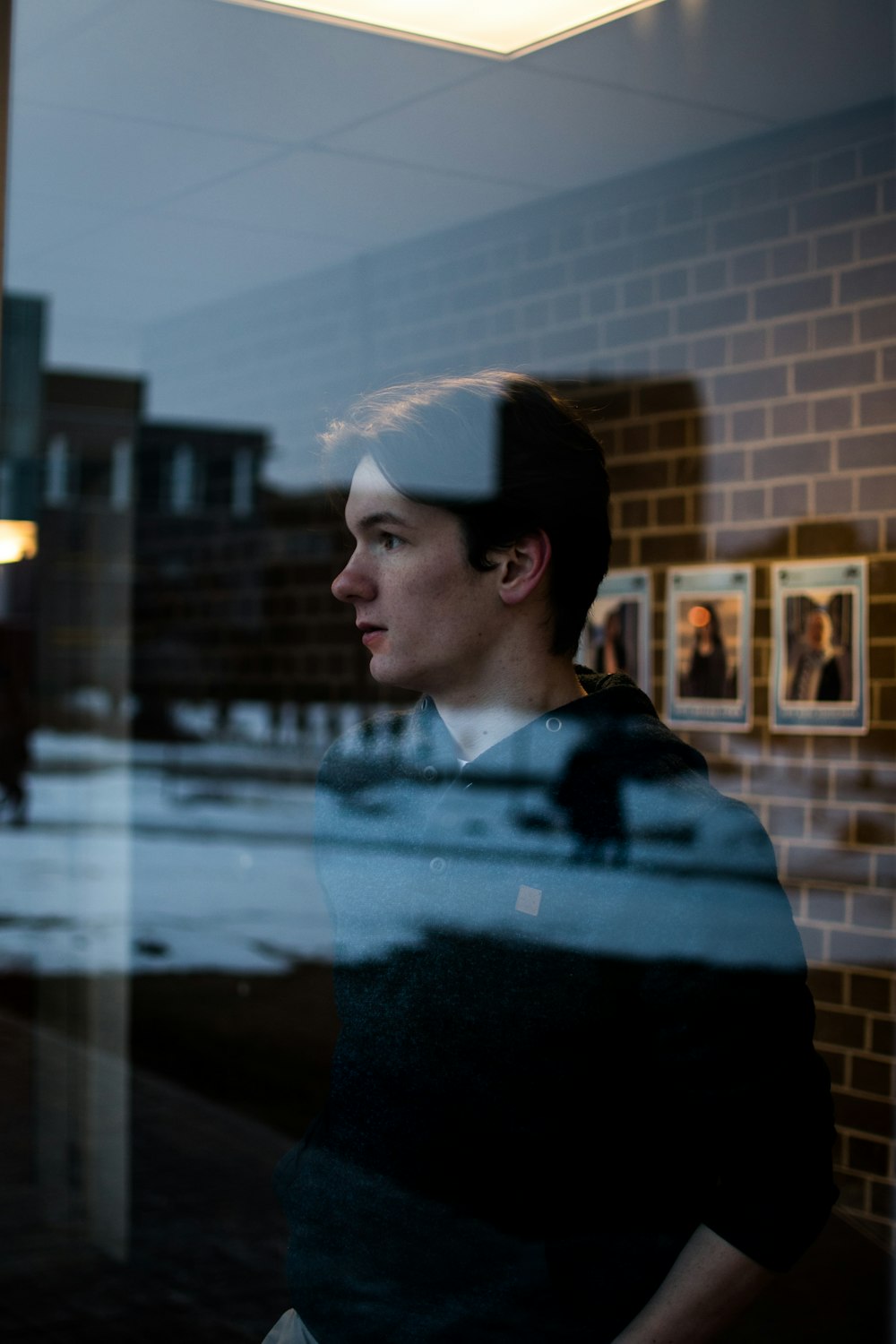 man in black sweater standing near glass window