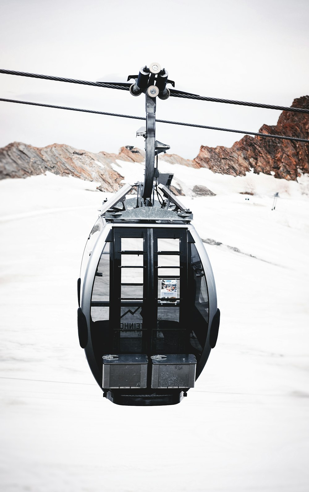 teleférico preto no chão coberto de neve durante o dia