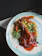 A close-up of a beautifully plated crispy duck dish with glossy ginger sauce and fresh herbs.
