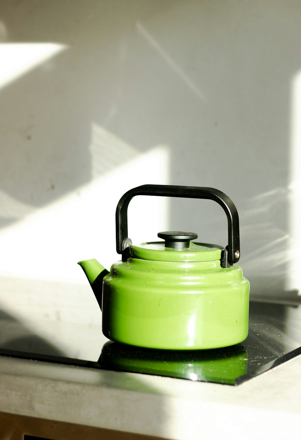 grüner und schwarzer Wasserkocher auf braunem Holztisch