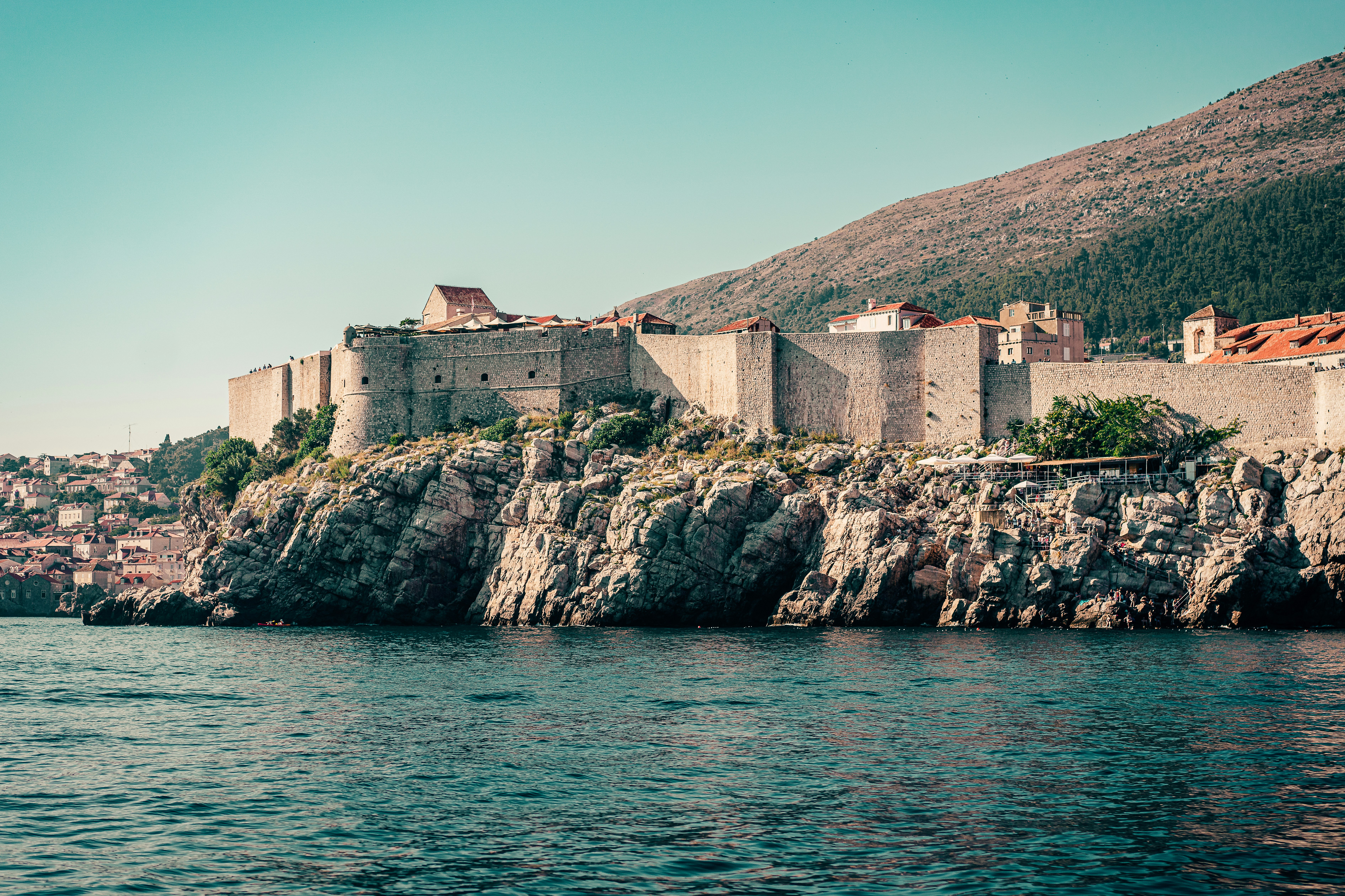 Brown concrete building on rock formation near body of water during daytime