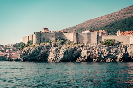 brown concrete building on rock formation near body of water during daytime in Dubrovnik Croatia