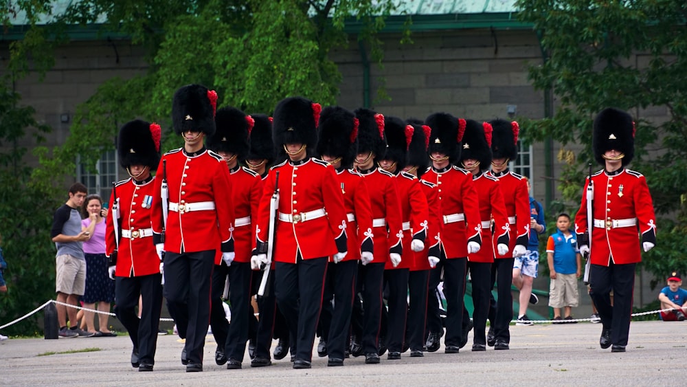 people in red and black uniform standing on gray pavement during daytime