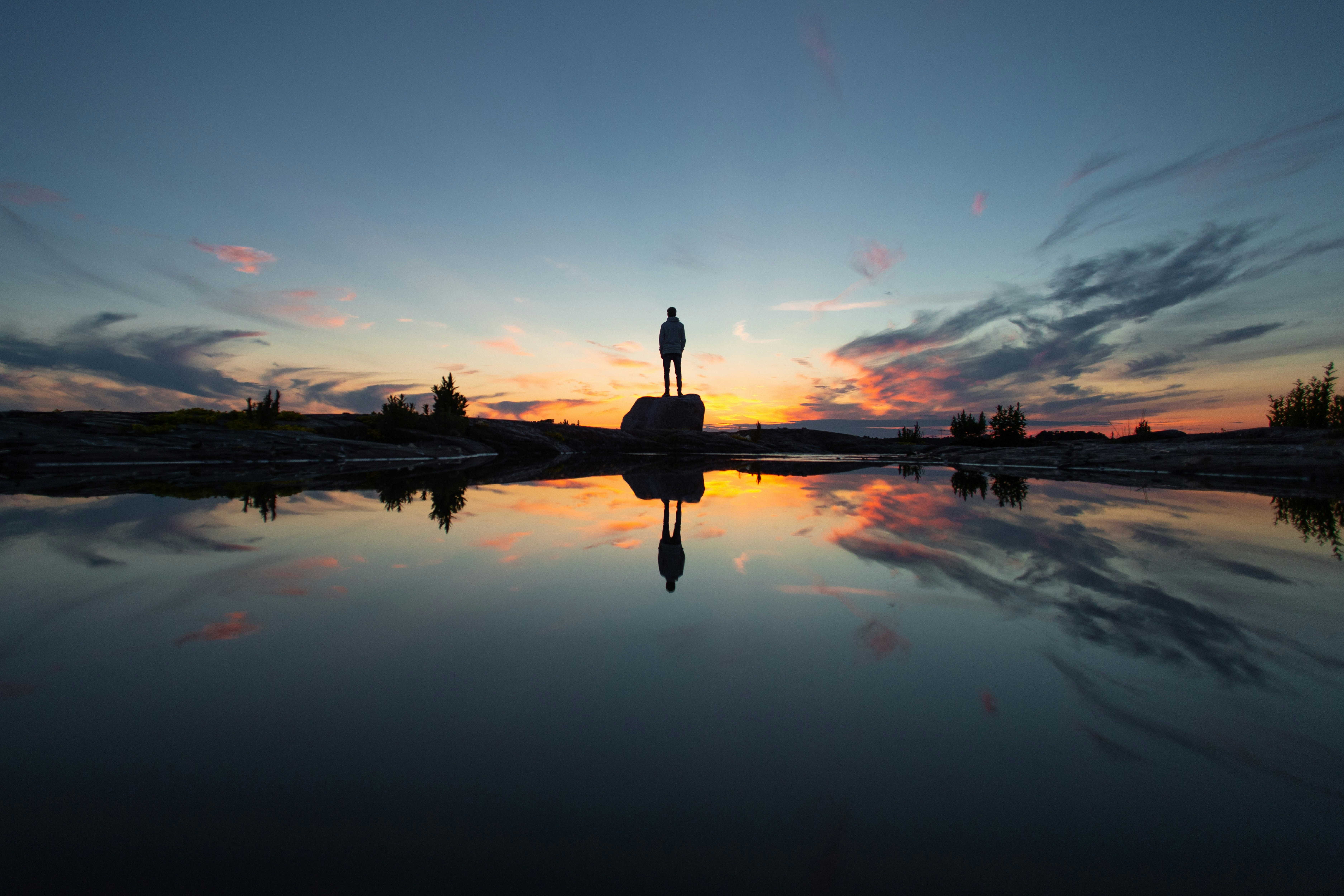 silhouette of man standing on dock during sunset
