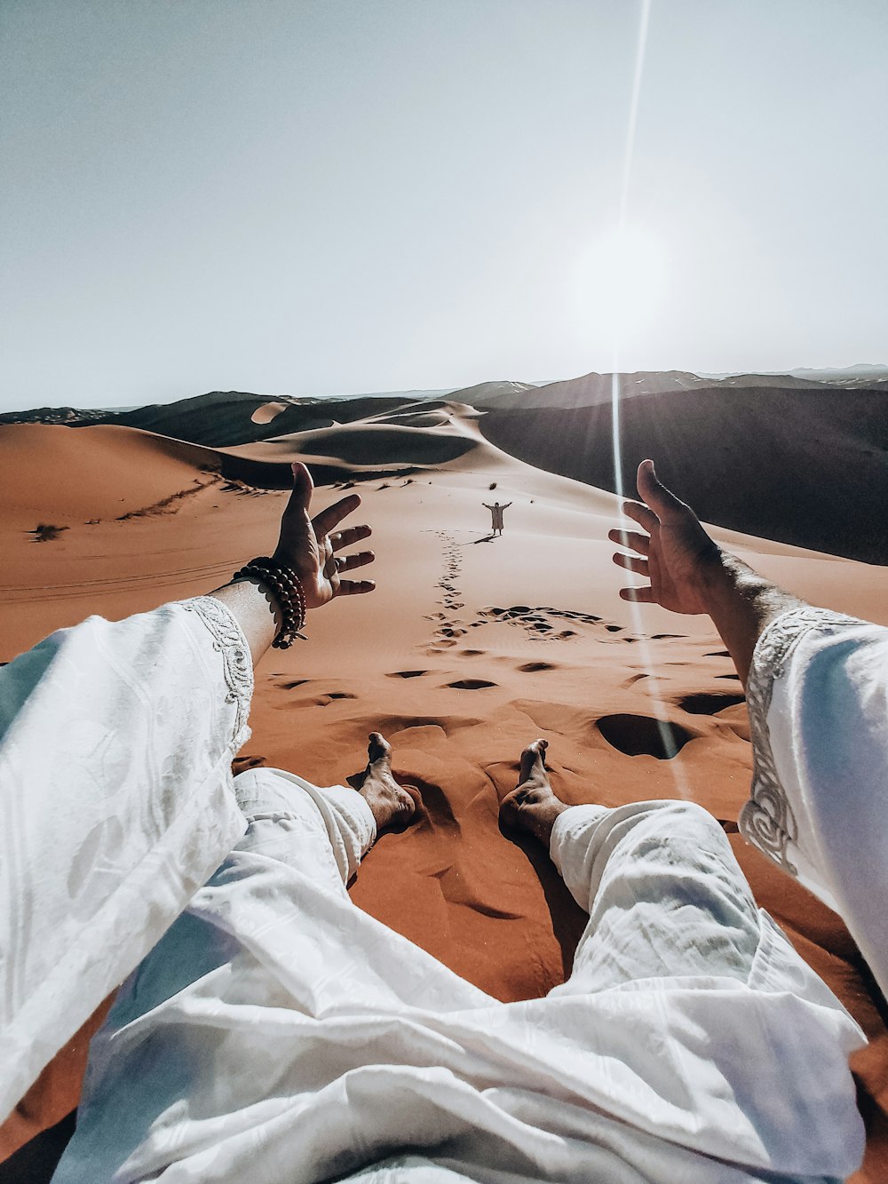 personne en jean bleu allongé sur le sable pendant la journée