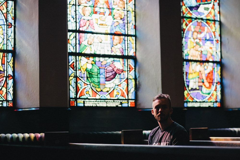 a man sitting in front of stained glass windows