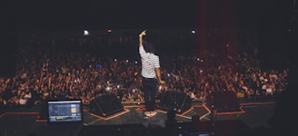 man in white and black striped shirt standing on stage
