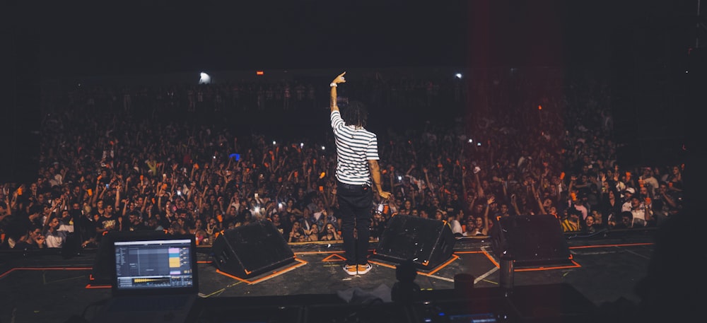 man in white and black striped shirt standing on stage