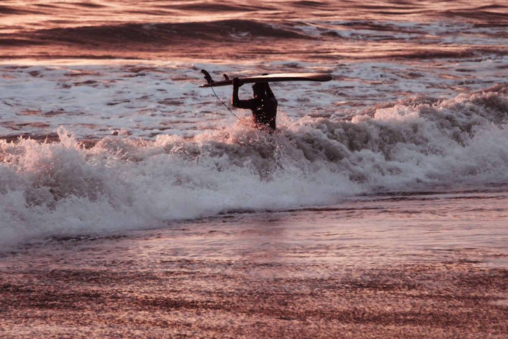 a man carrying a surfboard into the ocean