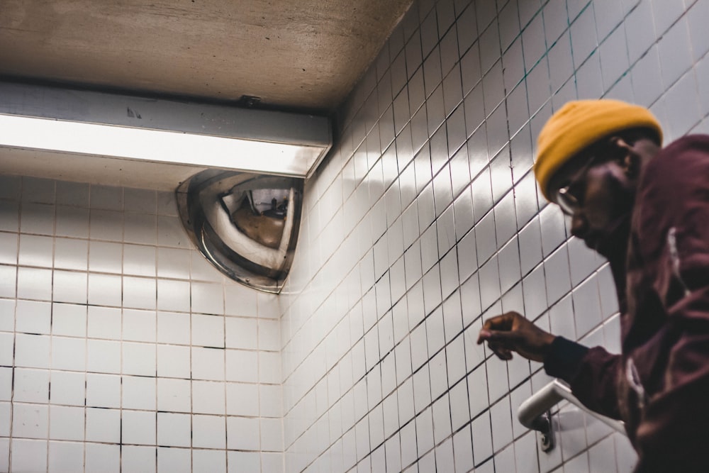 man in black jacket and yellow knit cap holding black smartphone