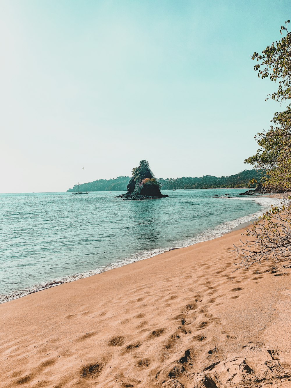 man in black jacket sitting on brown sand near body of water during daytime